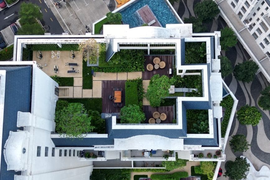 A planted rooftop garden with seating overlooking a dense Asian city skyline